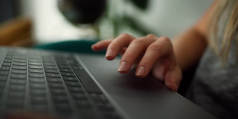 A woman moves her fingers on the track pad of a laptop
