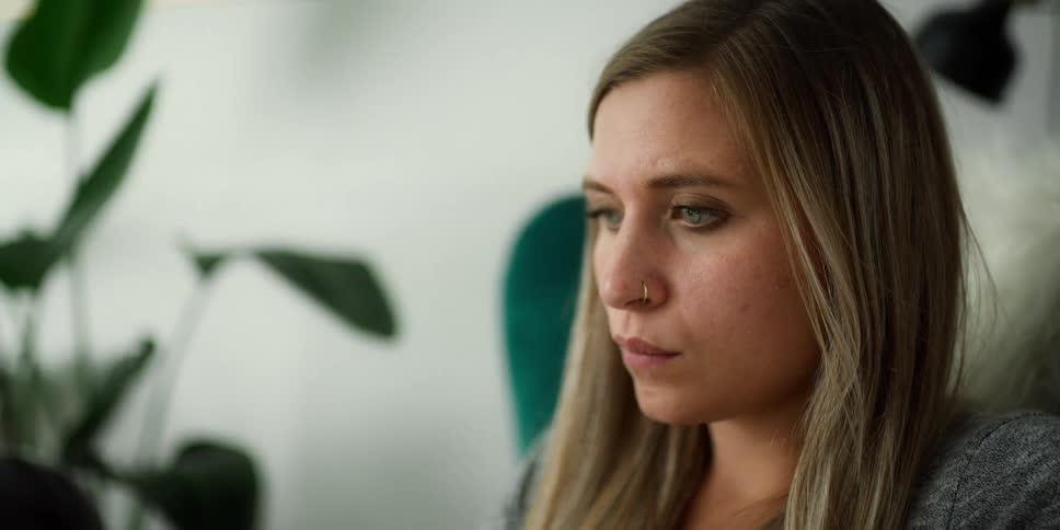 Blonde woman with nose ring and grey shirt uses laptop