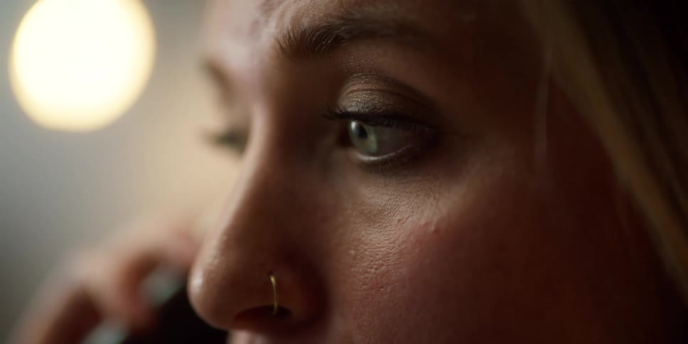 A close up shows a womans eyes moving around as she carries on a phone conversation