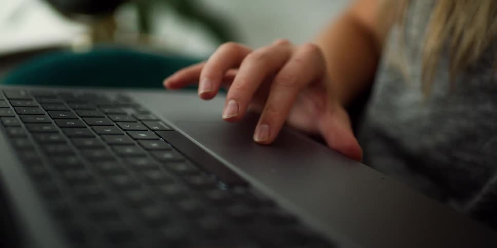 A person in a room using a laptop with a wall in the background