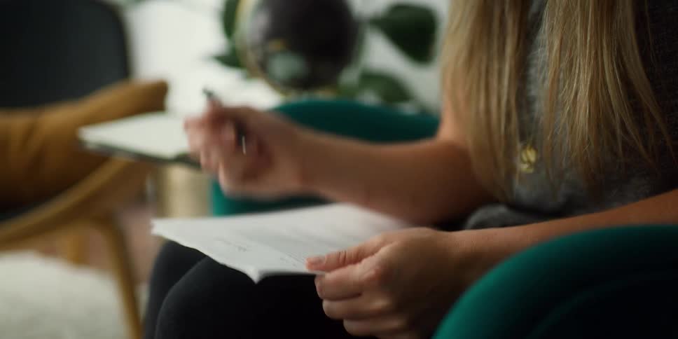 A woman writing on a piece of paper in a room