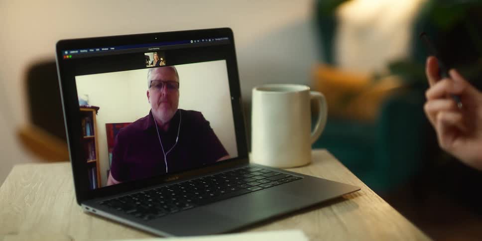 A person gestures with their hands while participating in a video chat with a laptop