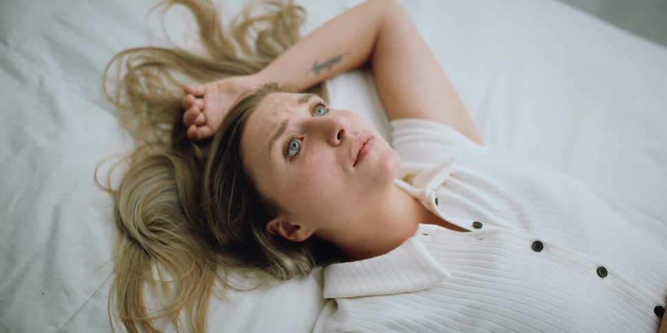 A woman lies on her bed lost in thought