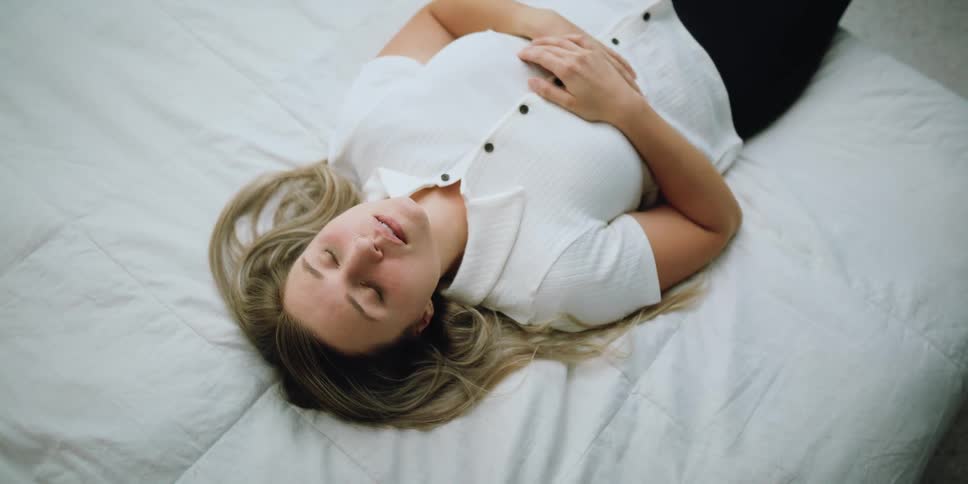 Young blonde woman laying on the bed in the bedroom at home looking tired
