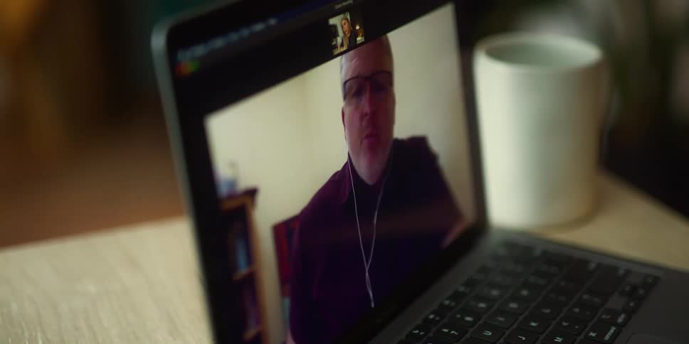 Woman makes video call with man on laptop next to white cup