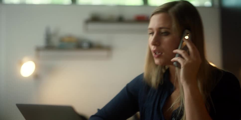 A woman talking on a phone in a room