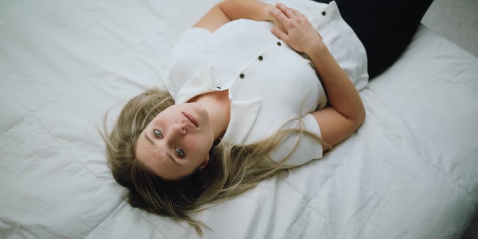 A woman lies on a bed and quickly becomes lost in thought
