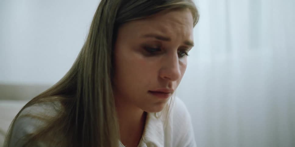A woman in a room with a bed a wall and window in the background