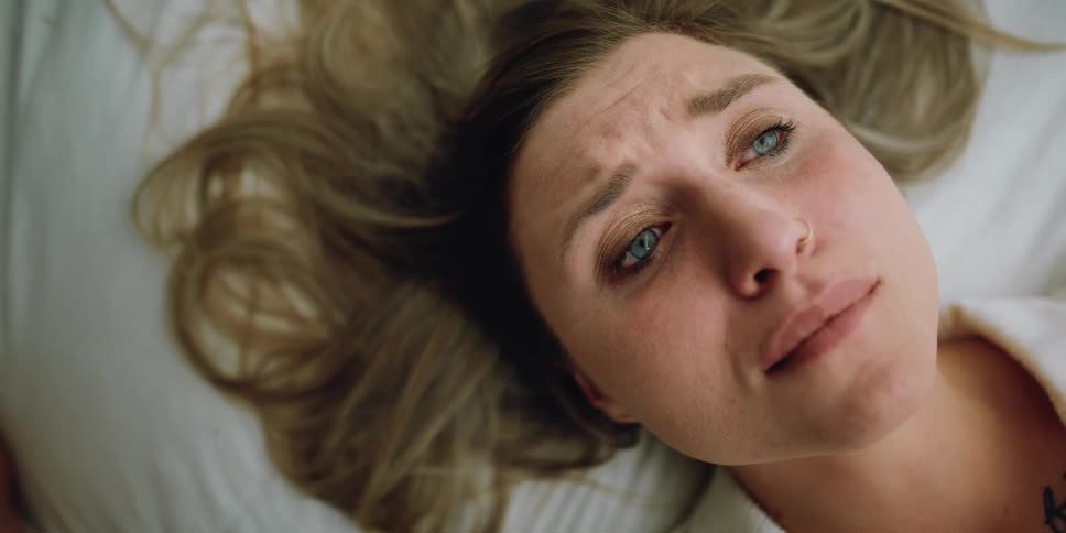 A woman is laying in bed crying