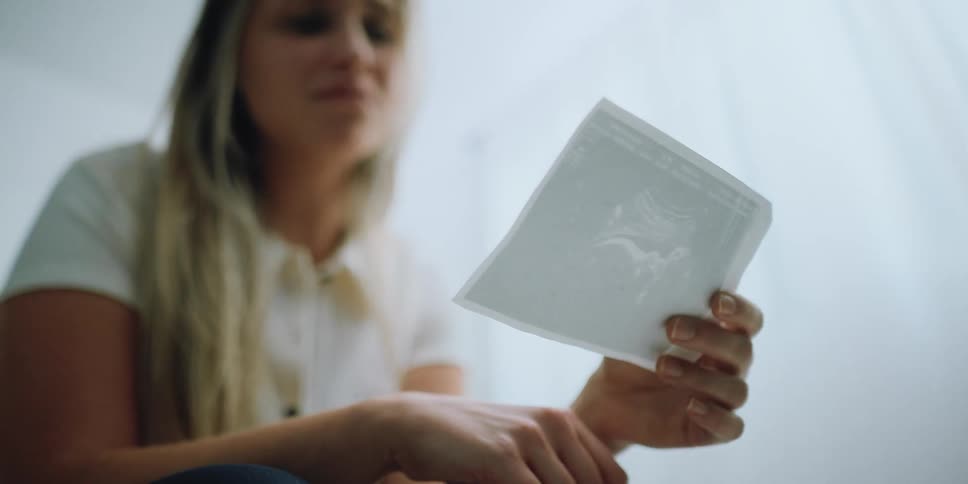 A sad woman crying while looking at a photograph
