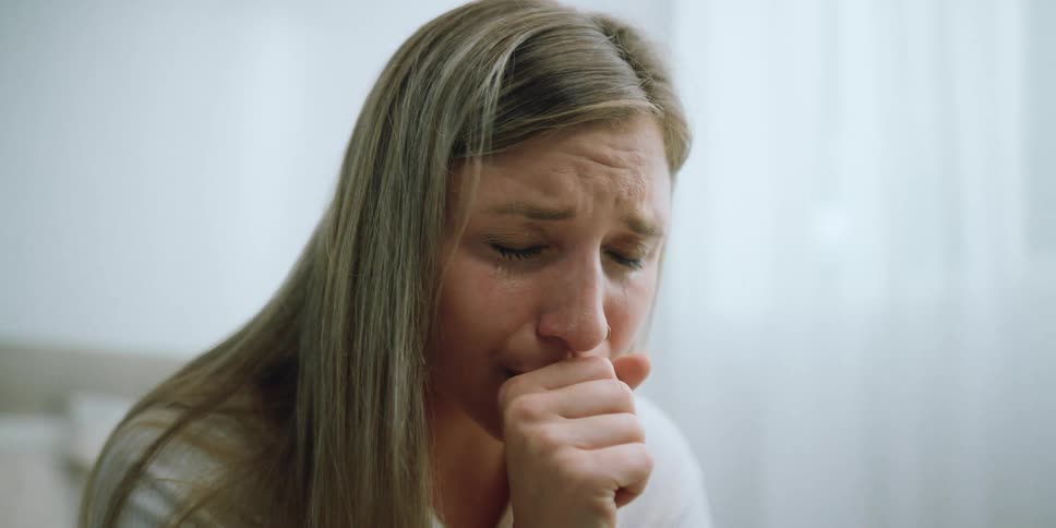 A woman sitting in a room and crying