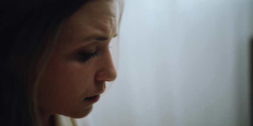 Blonde woman with white shirt looks down at baby picture getting emotional