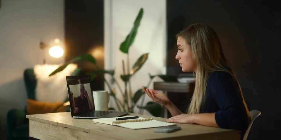 A woman gestures with her hand as she talks to a colleague during a zoom meeting