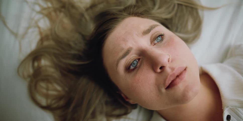A sad woman laying on the bed
