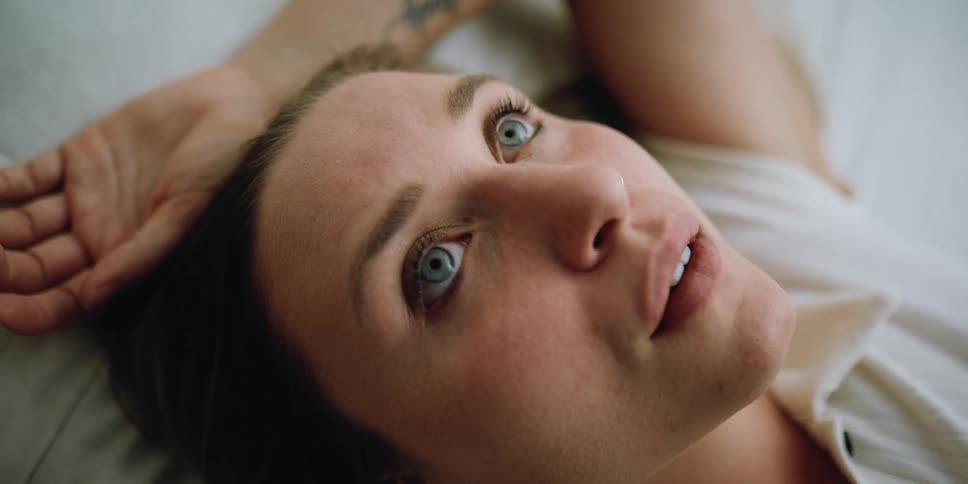 A woman thinking while lying in bed with her eyes open