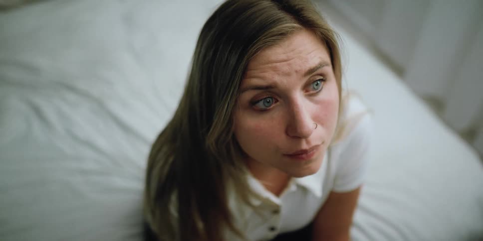 A woman that is sitting on the edge of a bed