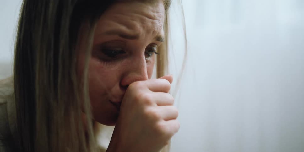 A woman sitting in a room and crying