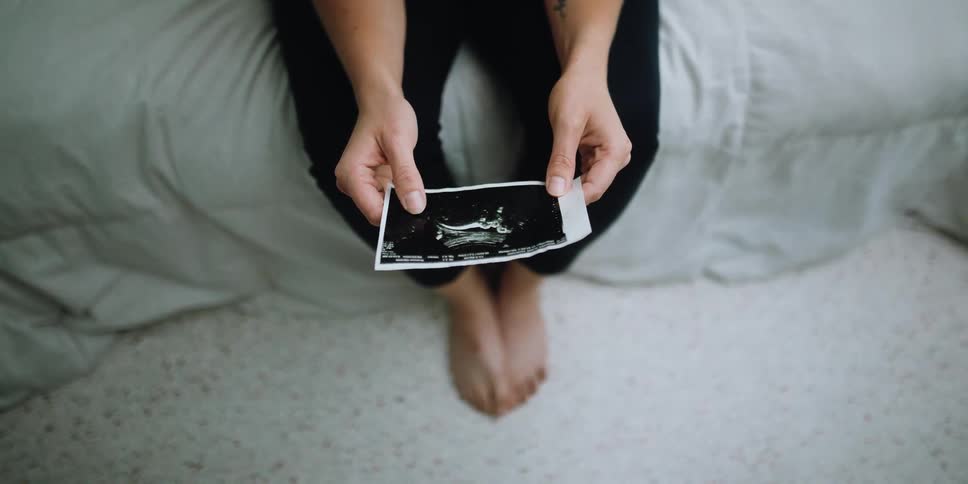 Woman sits and looks at an ultrasound photo
