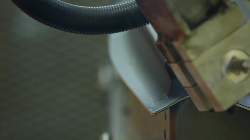 Power tool cuts into flexible black material edging metal labeled with barcode