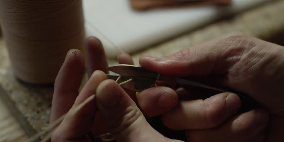 A man snips a thick piece of thread