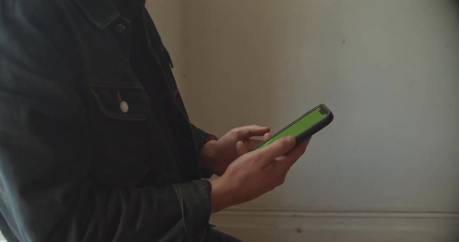A man standing by a window with a phone