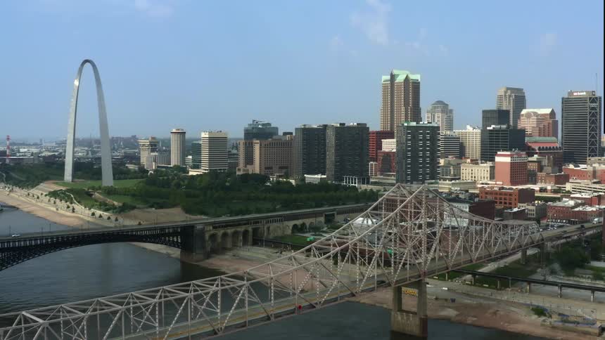 A white arch is on the river front of a large city