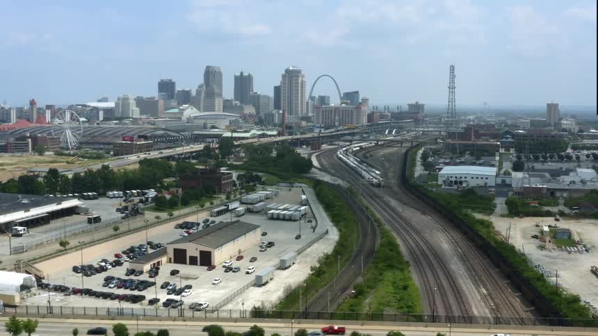 A city skyline with buildings and skyscrapers streets and a ferris wheel with the sky and clouds in the background