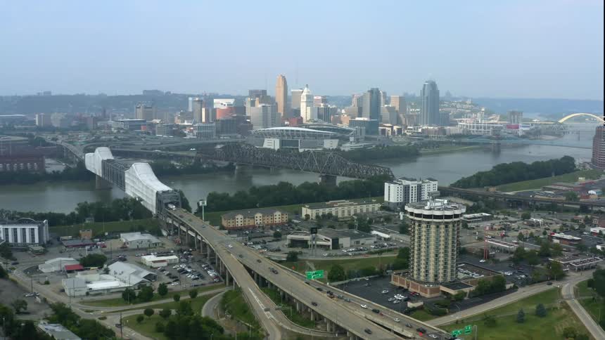 Mist covers horizon as traffic travels along highways toward city over bridges crossing river
