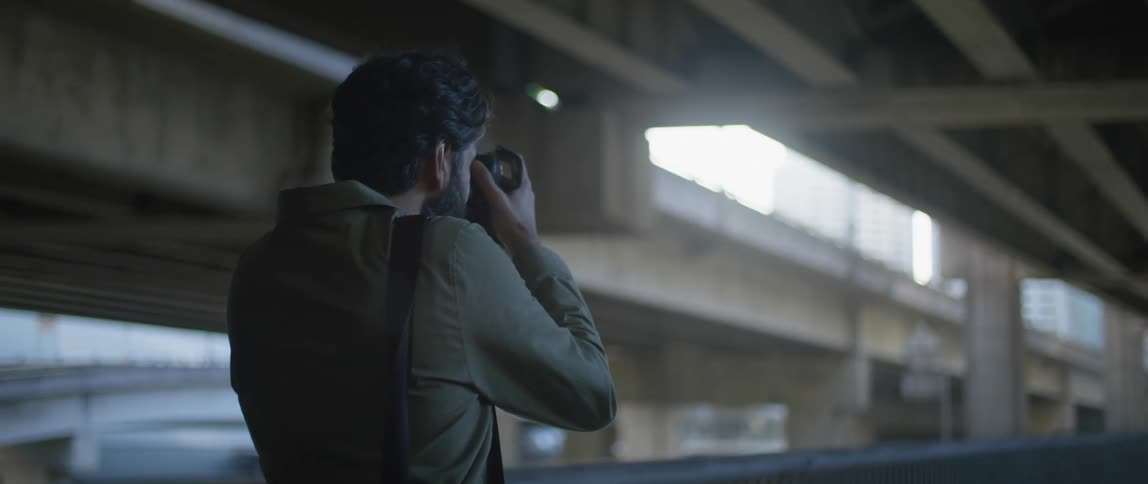 Photographer takes picture of buildings shining through underpass as he stands beneath them
