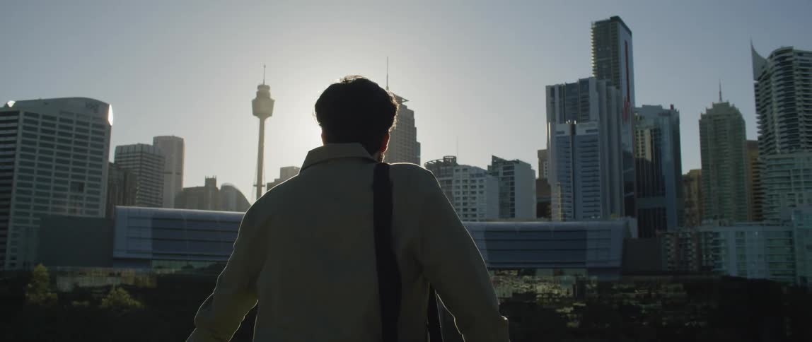 A man looks out over the city at sunrise