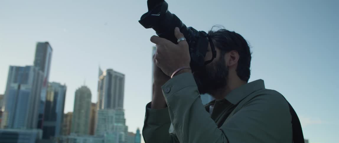 Young bearded man takes pictures of the city at sunset