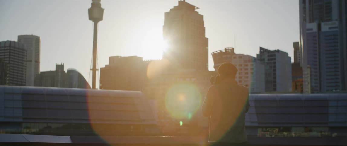 Photographer uses a camera to take pictures of the buildings on a city at sunset