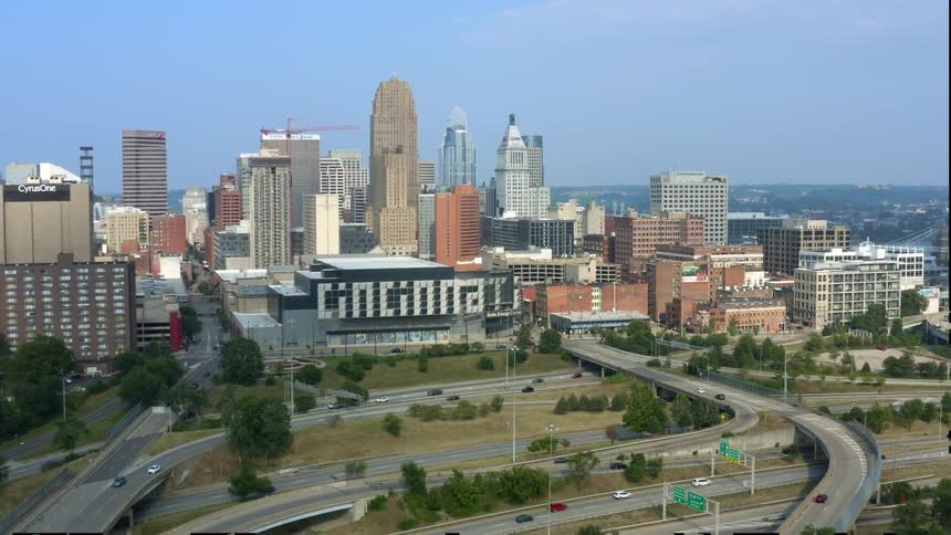 Aerial view of a city with cars driving on roads and tall buildings visible at a distance