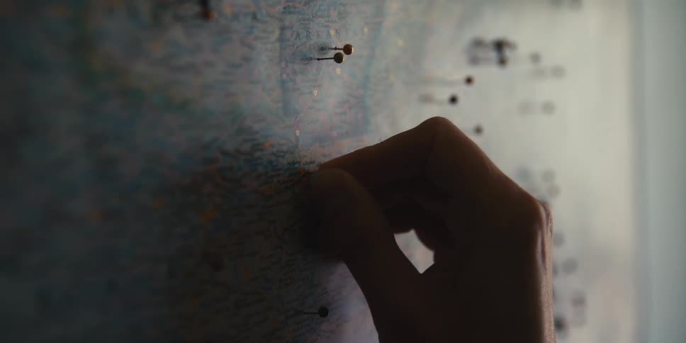 Hand placing a pin on a map hanging on the wall