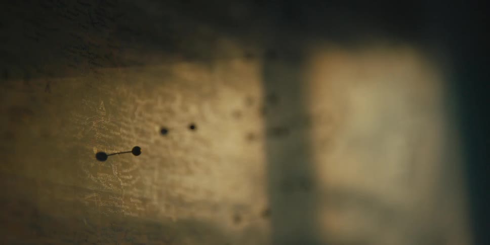 Sunlight casts a shadow on a wall with pins in it