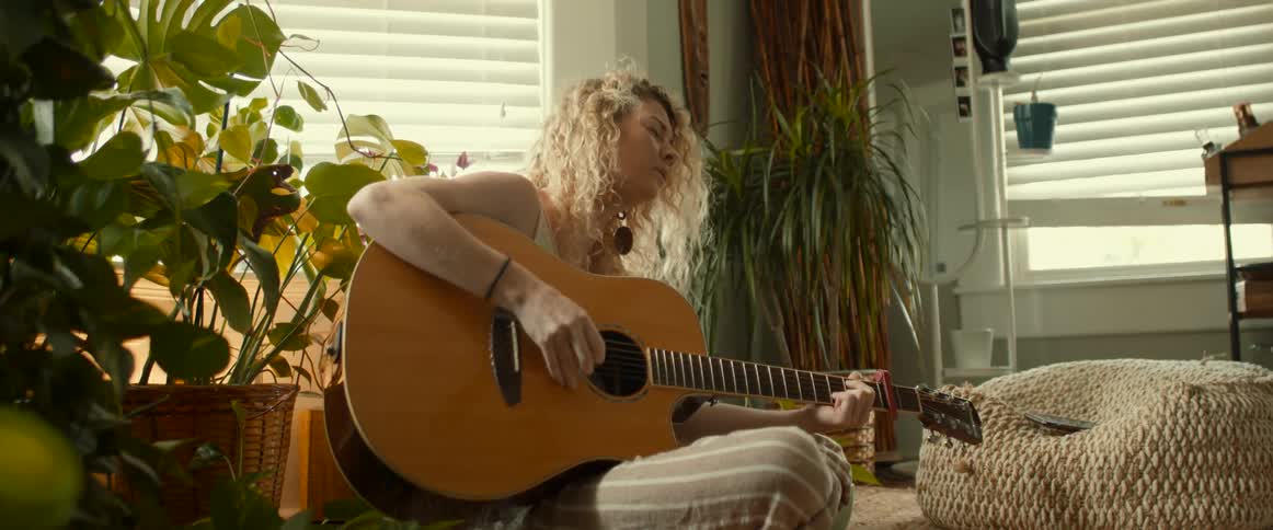A woman playing a guitar in a house