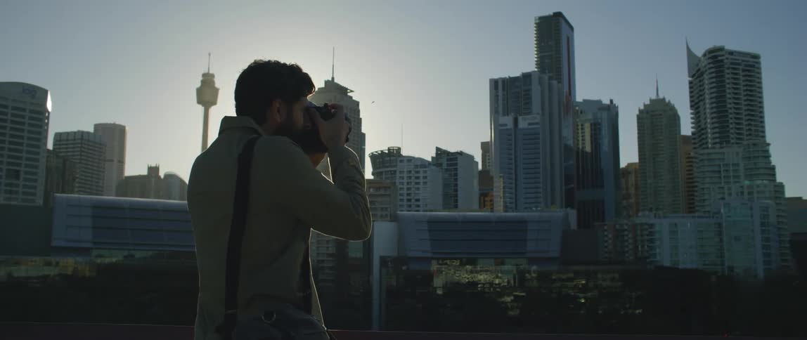 A male photographer taking pictures of skyscrapers in a city on a sunny day