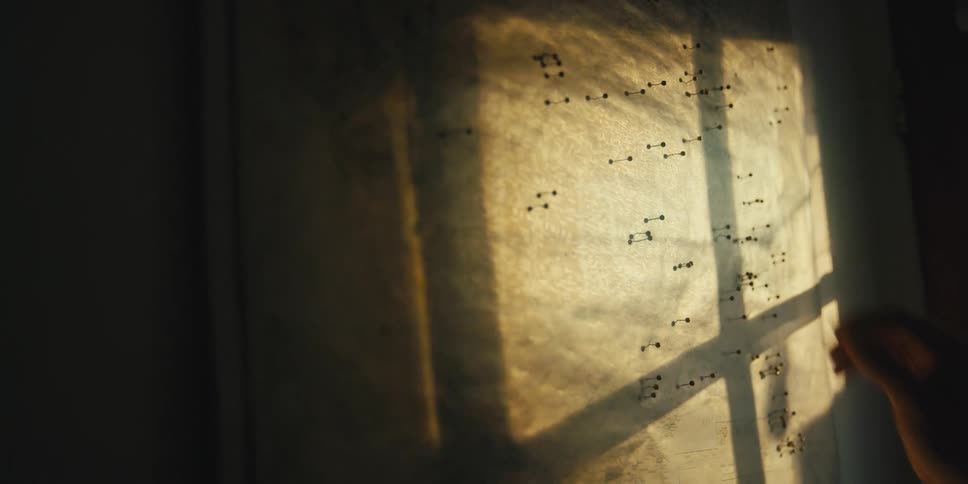 Push pins being applied to a large piece of paper that is covering a window