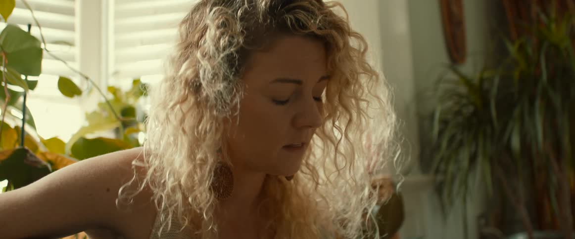 Blonde woman with wavy hair plays guitar and sings a song