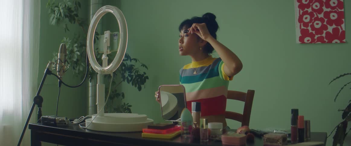 A woman records herself putting on makeup while talking into her smart phone
