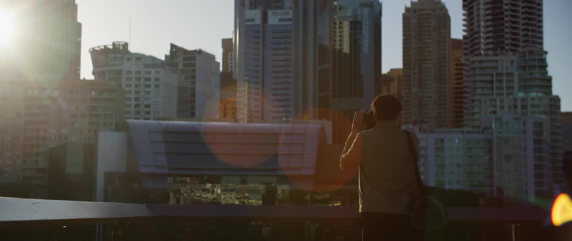 A male photographer taking pictures of city skyscrapers in the distance