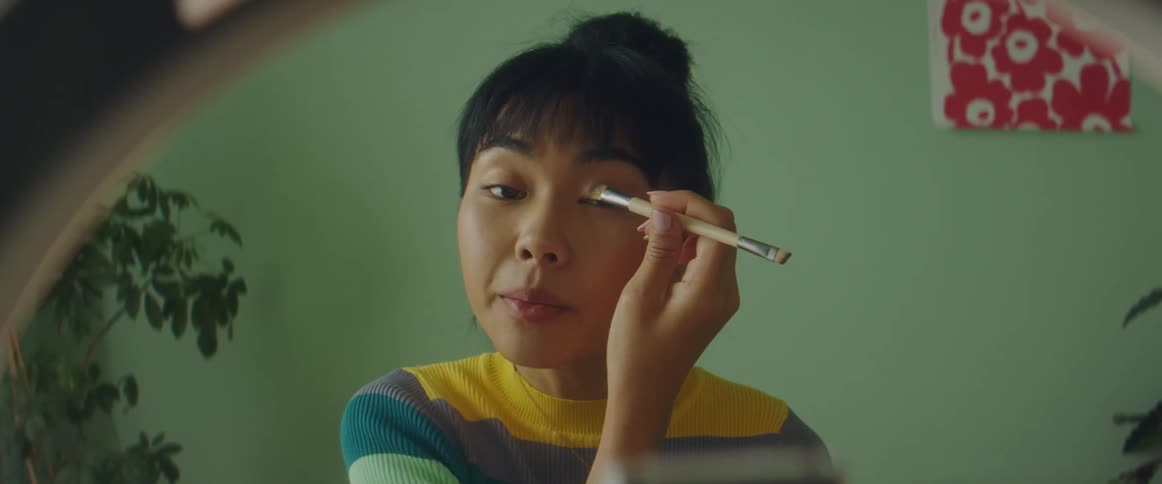 A woman putting on makeup in a studio
