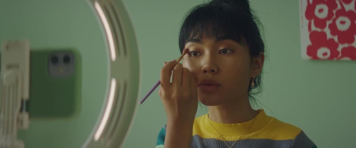 A woman is putting on makeup and filming it