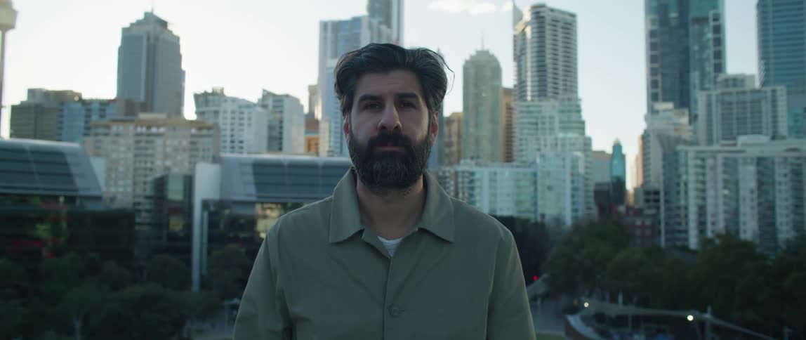 A man is standing still with a large city as a backdrop