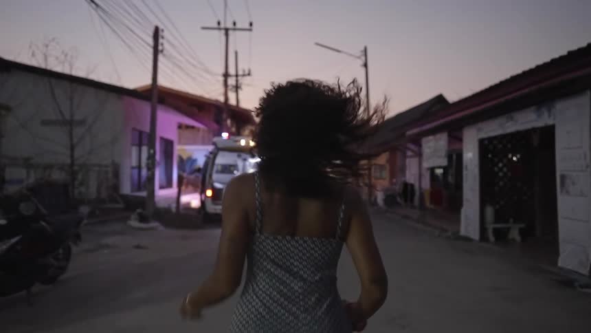 A woman running towards an ambulance with utility poles houses the sky and clouds in the background