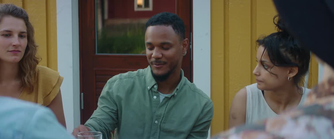Group of friends sitting at the table in the backyard eating and talking