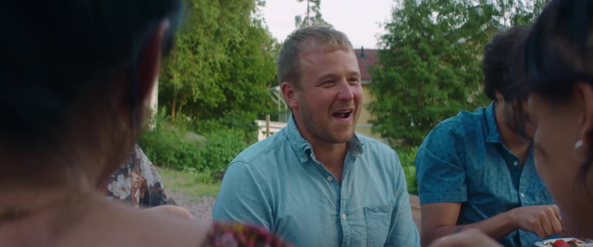 A group of people are laughing and enjoying a meal together outside