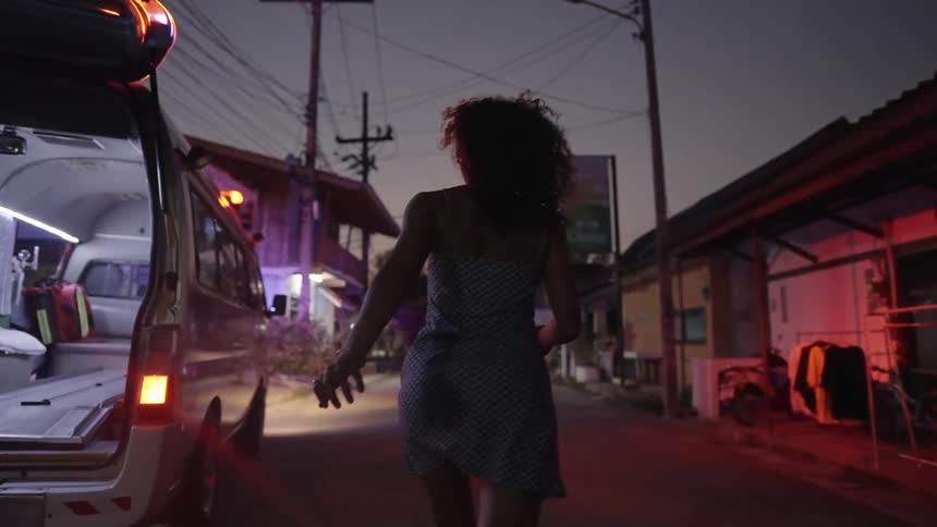 Woman runs down street past stores heading toward area ambulance is parked by