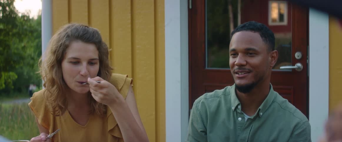 A man and woman sitting outside talking and eating