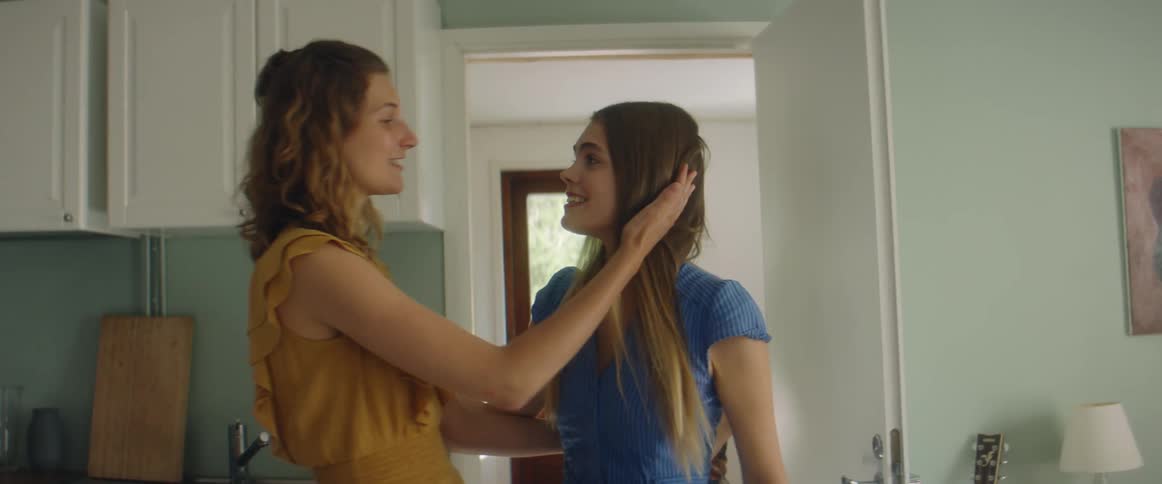A woman hugging two friends in a house